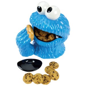 Cookie jar shaped like the cookie monsters head, with the cookies in his mouth and a hand reaching up to feed him another cookie