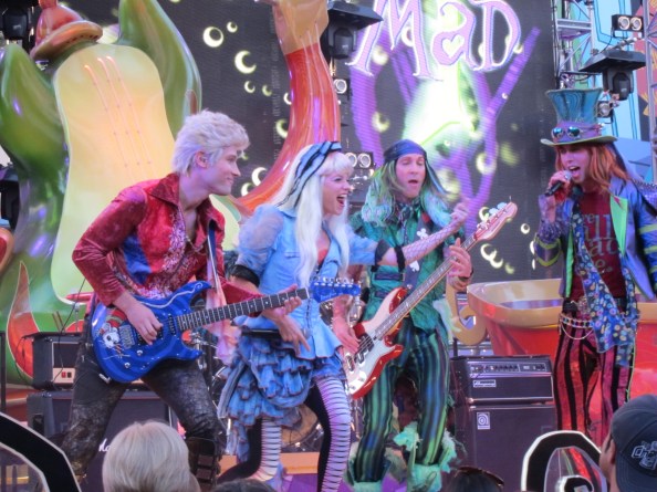 The Mad T Party Band in concert - featuring the white rabbit (guitar), Alice (vocals), the march hare (bass) and the mad hatter (lead vocals).