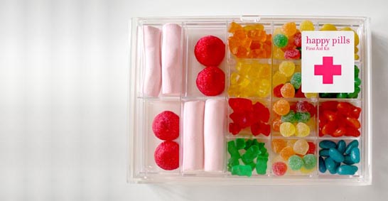 Pill box with the label "Happy Pills First Aid Kit" and a red cross, with the little pill sections filled with lollies of various kinds.