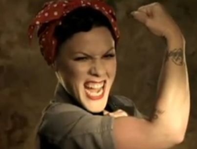 Pink doing a pose reminiscent of the 1940s propaganda campaign image 'Rosie the Riveter'. A young woman in a blue work shirt and red bandanna with white spots, holding up her arm to show her bicep, and implicitly, her strength. The caption on the original image reads 'we can do it', while it is not visible here, this image is taken from the video clip for the song 'raise your glass'