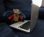 Foot-high Chistery (flying monkey from Wizard of Oz) sitting on a blue couch with a laptop on his lap.
