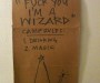 Piece of cardboard on which is written -- Camp 'Fuck You I'm a Wizard' Camp Rules: 1. Drinking, 2. Magic (and then there's a sketch of a pointy wizard hat and wand)