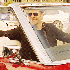 Chris Pine (Jim Kirk) in the driver's seat of a convertible throwing back his head and laughing.